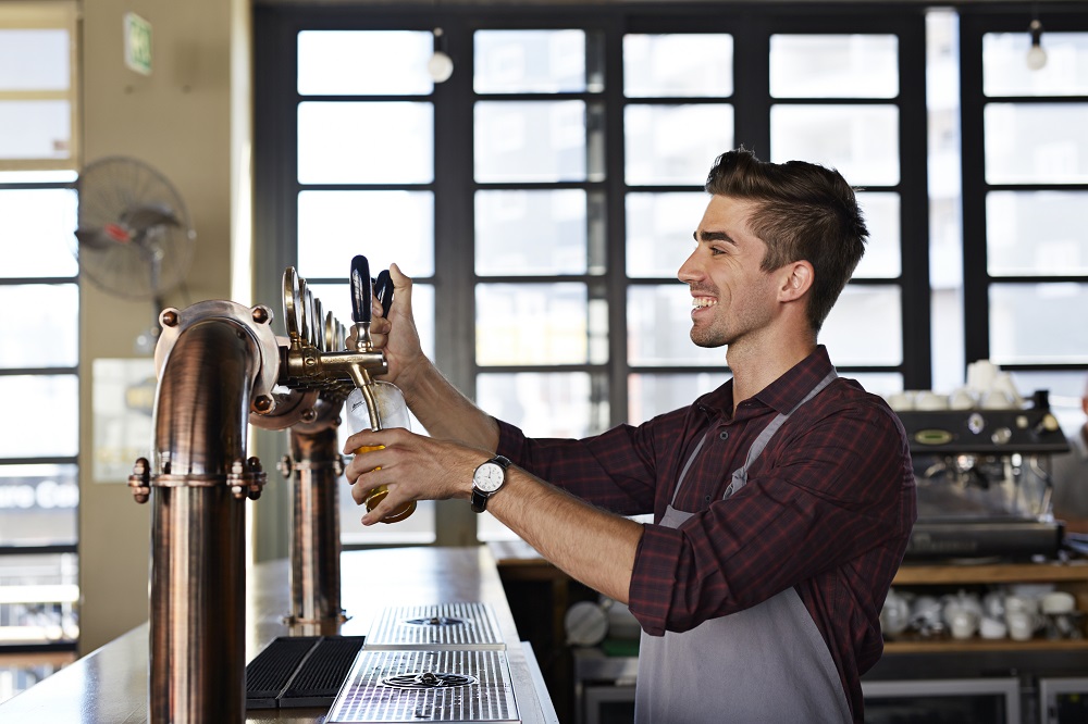 A man is seen pouring beer into a glass, representing camaraderie and enjoyment in a workplace environment.