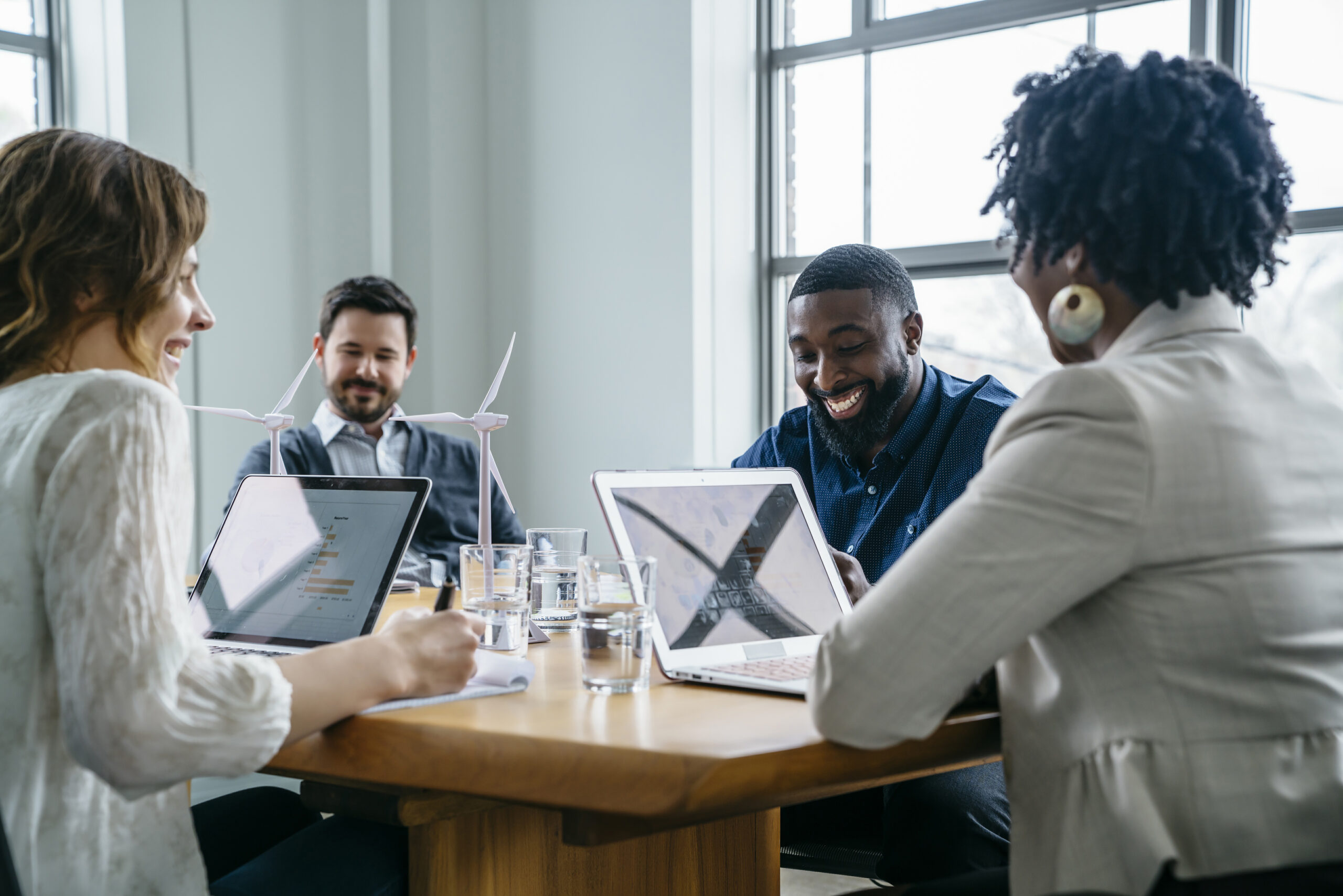 Four professionals sitting around a table and working on laptops